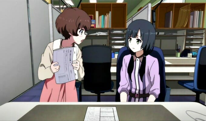 Shirobako - Ema and Ai discuss a task at Ema's desk.