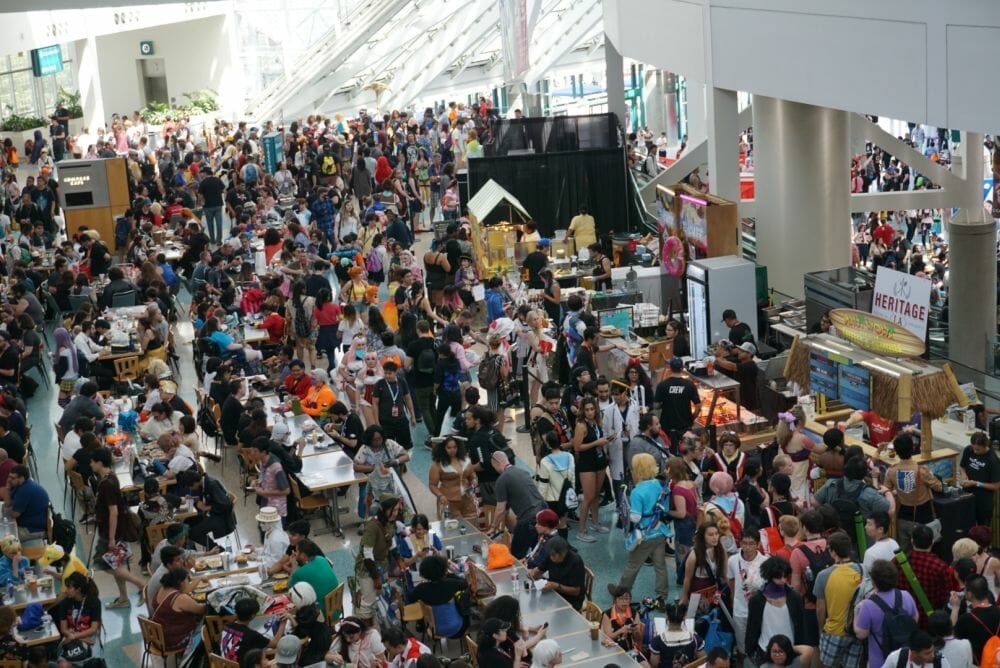 An overhead photograph of the Anime Expo main floor. The tile is completely obscured by people.