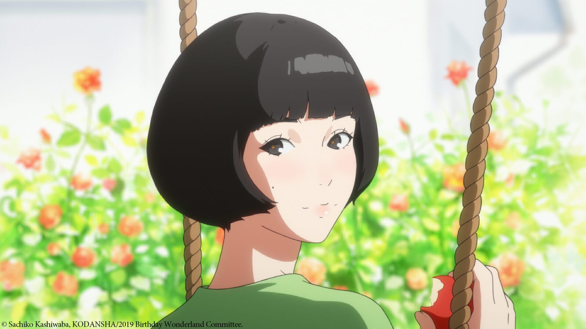 A woman with a bob haircut stands against a field of flowers. She's holding a broom.