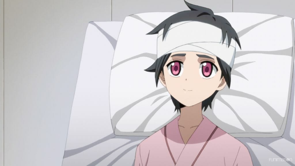 Id Invaded Episode 3 Still - Hondomachi smiles as she looks at the camera. She's wearing a pink hospital gown, and her head is wrapped in a bandage.
