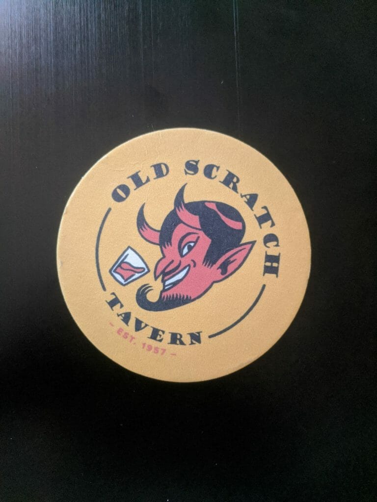 Photo of a coaster with a cartoon devil. The text reads "Old Scratch Tavern."