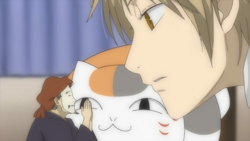 Natsume's Book of Friends Anime Still - A man with blonde hair talks to a tiny man wearing a mask. A cat watches from the background.