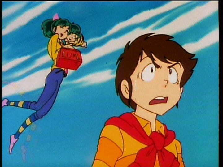 Urusei Yatsura Anime Still - A brown-haired man in a yellow top looks to the right. Behind him, a green-haired girl wearing jeans and a yellow top floats as she hugs a small green-haired child.