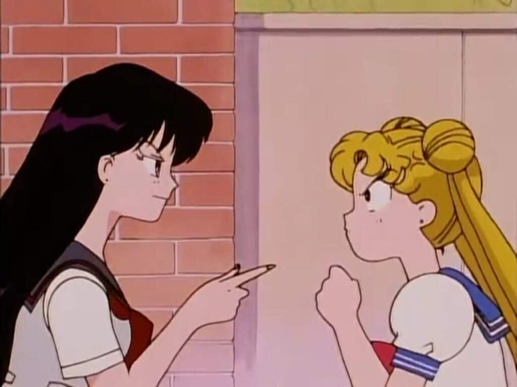 A blonde girl and a black-haired girl stare angrily at each other.