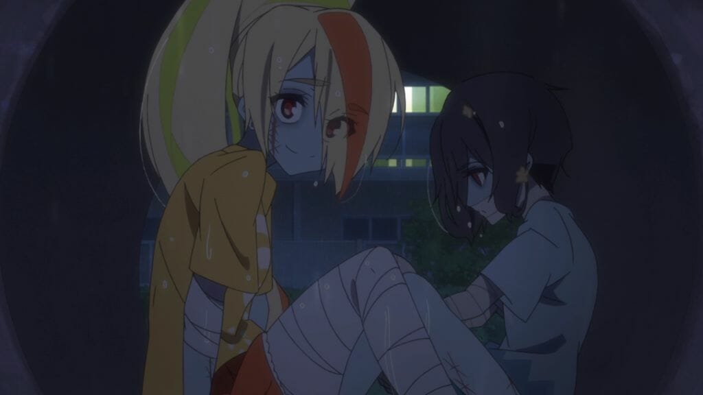 Still from Zombie Land Saga Episode 6, which depicts a blonde zombie woman and a black-haired zombie woman sitting in a pipe as rain pours outside. 