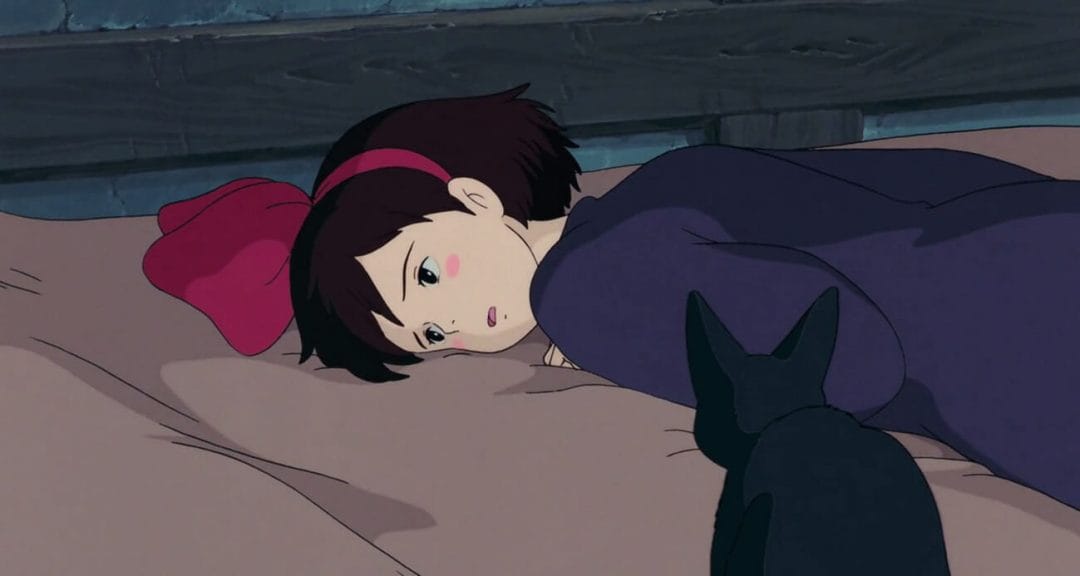 Still from Kiki's Delivery Service, which features Kiki laying, listless, on a beige sheet.