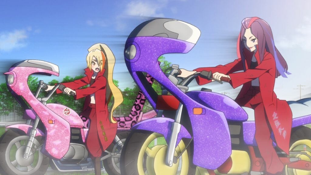 Still from Zombie Land Saga Episode 9, which features Saki and a purple-haired woman. Both are wearing heavy red coats as they ride glittery motorcycles