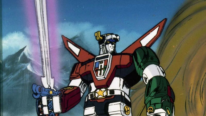 Upper body shot of Voltron: a giant multicolored robot holding a pink laser sword.
