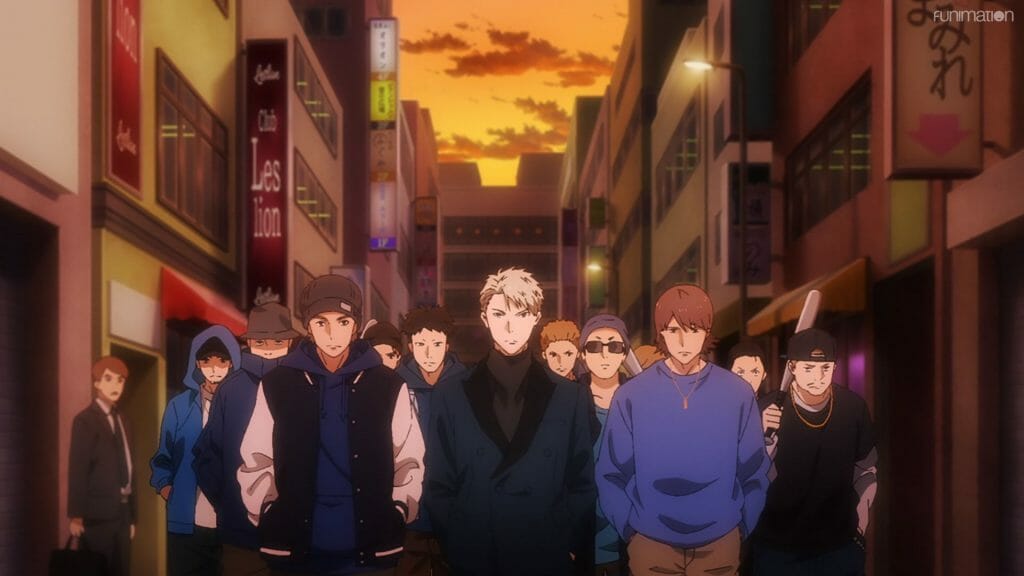 Still from Ikebukuro West Gate Park that depicts a blonde man in a suit, who stands in front of a crowd of people in blue.