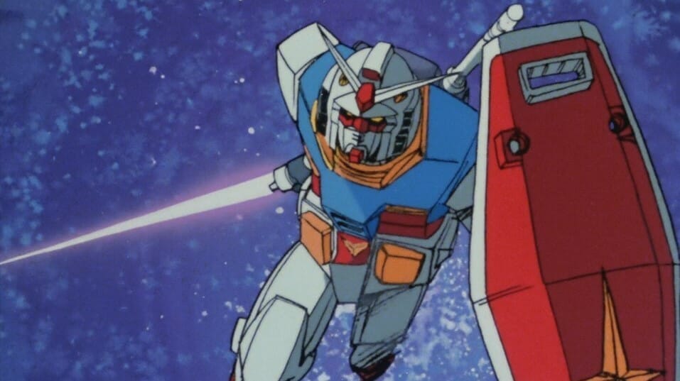 Front shot of the RX-78-2 Gundam, a white robot with red and blue accents, as it charges into battle. It is holding a shield and a laser sword.