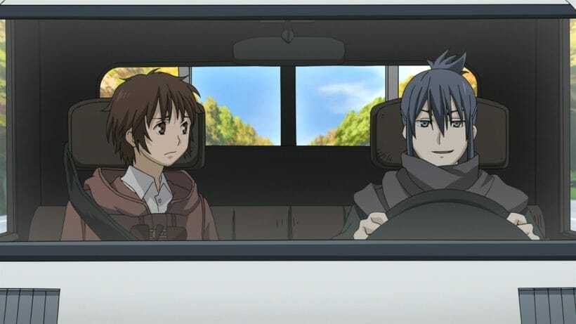Still from No. 6, depicting  a brown haired man and a dark haired man in a truck. The dark haired man smirks as he sits behind the wheel.
