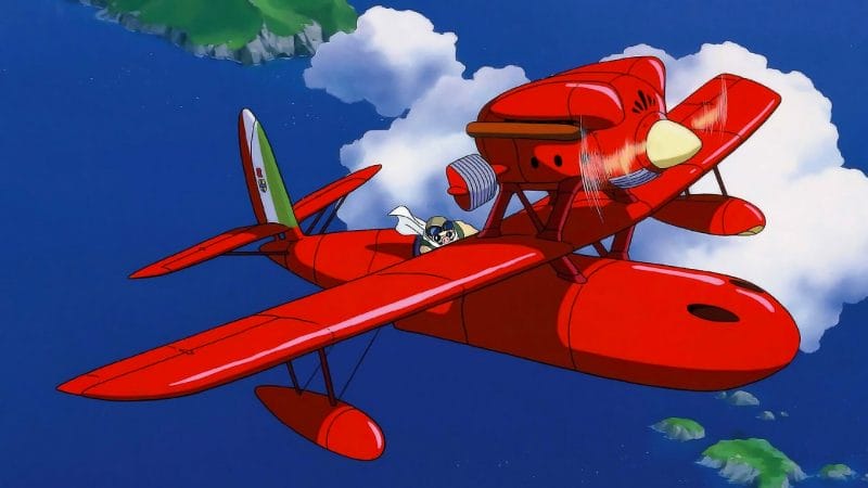 Still from Porco Rosso that depicts Porco flying in a red fighter plane. The blue sea can be seen below.