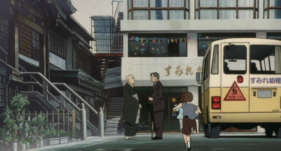 Still from WXIII: Patlabor the Movie 3 that features two men talking on a busy street in Tokyo. A yellow van sits on the right side of the frame.