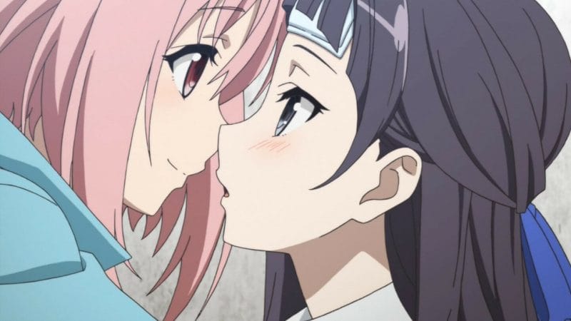Still from Sakura Quest - a black-haired woman blushes as she leans close to a woman with pink hair.