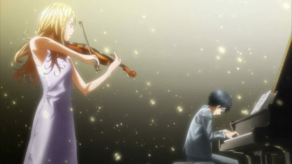 A man in a grey suit plays the piano, his back to a blonde woman clad in white, playing the violin. The two are lit from above by a spotlight.