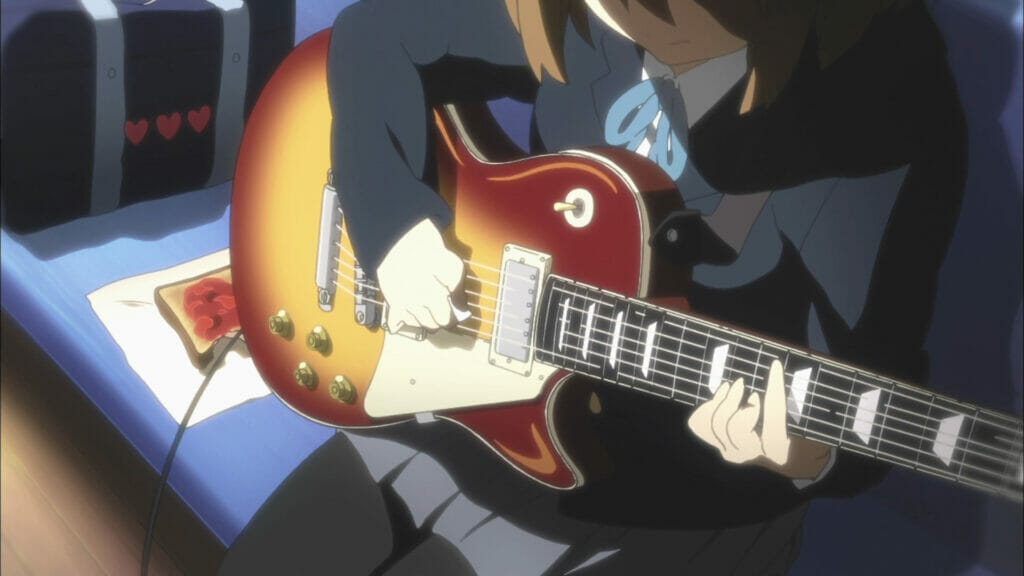 Closeup of Yui playing her crimson and gold guitar