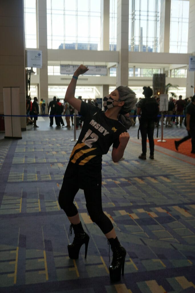 Photo from Otakon 2021 - A woman with short grey hear, wearing an MSBY jersey, poses triumphantly