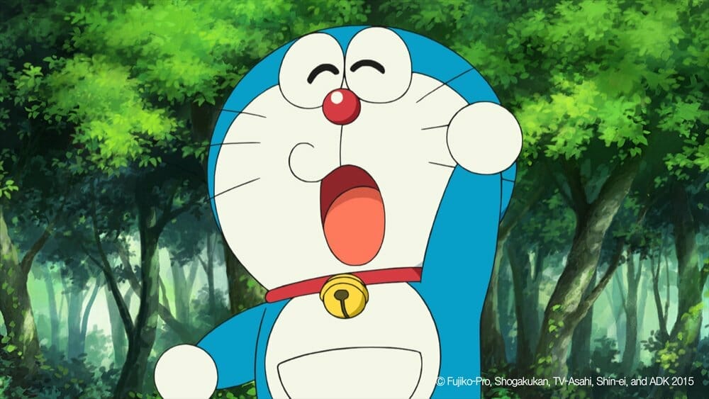 Doraemon, a blue cat robot, smiles and waves at the camera.