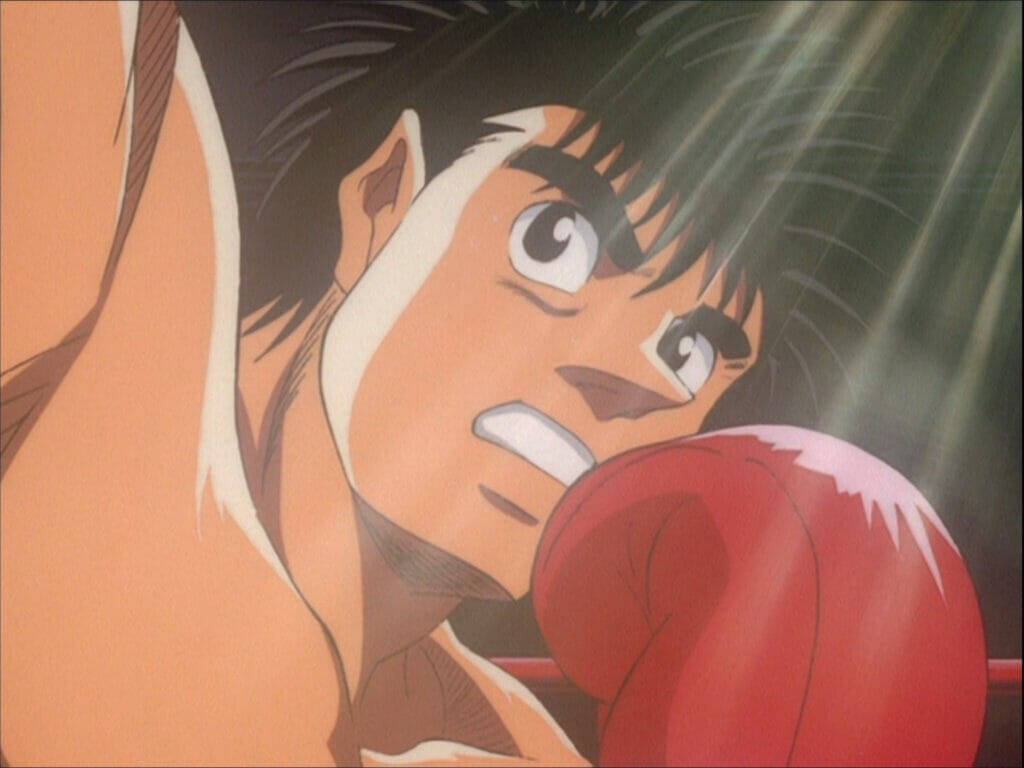 Screenshot from Hajime no Ippo, in which a black-haired man in boxing gloves punches offscreen.