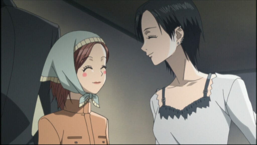 Still from the Nana anime, featuring a brown-haired woman in a scarf and tan shirt smiling at a woman with short dark hair.