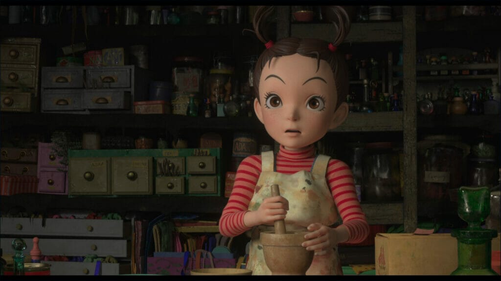 Screenshot from Earwig and the Witch, which depicts a young girl in a grey jumper and pink shirt holding a mortar and pestle.