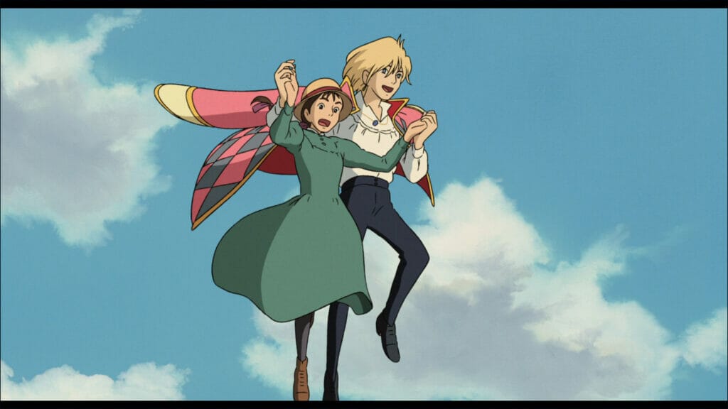 Screenshot from Howl's Moving Castle, which features a blonde man in a pink cloak and a young woman in a green dress soaring through the sky. The girl in the green dress is wearing a look of surprise on her face.