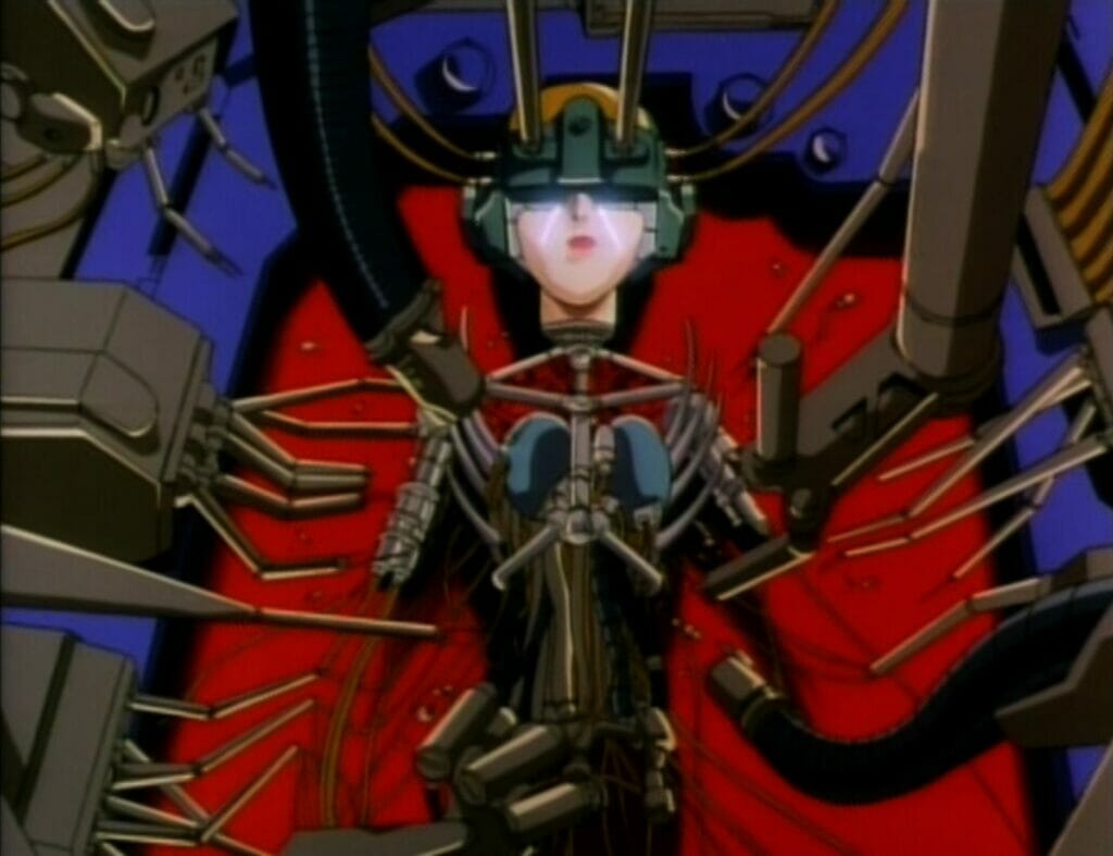 Screenshot from Genocyber. A robotic woman with short brown hair cut in a bob weeps as a machine tears her apart, leaving just a metallic skeleton.