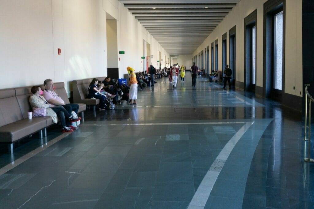 Photo of a quiet hallway, as a handful of people mill about along the sides.