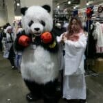 Photo of a couple of cosplayers at Anime Boston 2023, dressed as Kuma from Tekken and a Shinto priestess