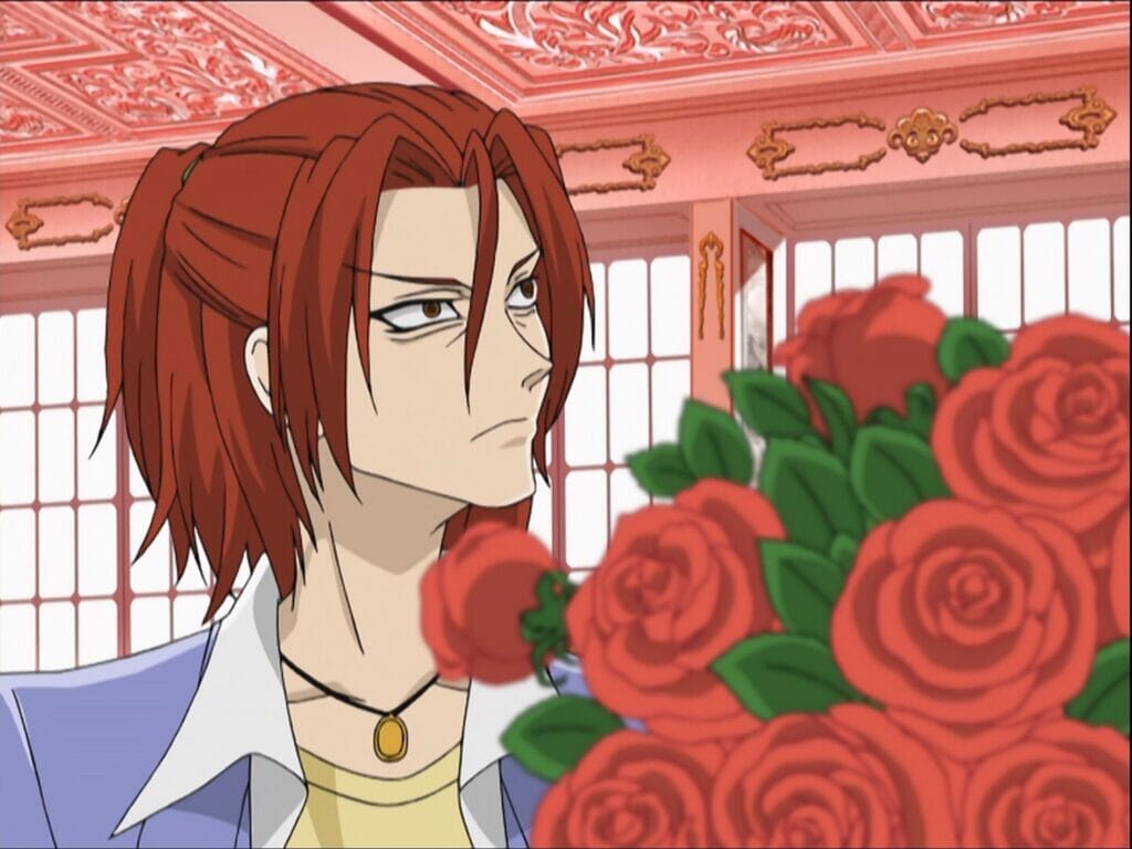 Screenshot from Ouran High School Host Club that depicts a red-haired man glaring offscreen as he sits next to a vase of roses.