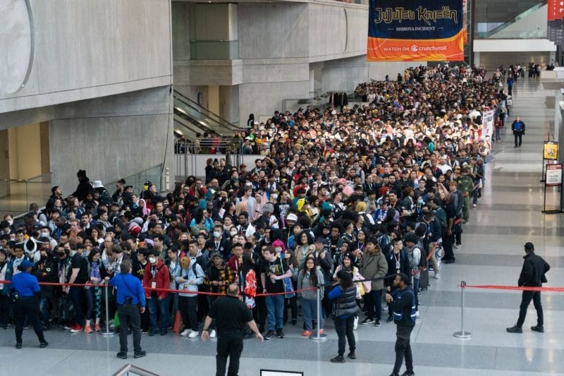 A crowd of people lined up at the entrance of Anime NYC 2023, held back only by a velvet rope.