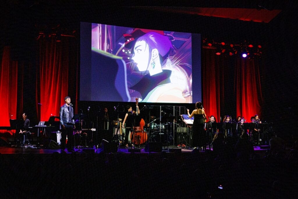 Photo of The Sinfionetta performing onstage at The Town Hall in front of a large screen, which features footage from the fifth episode of Cowboy Bebop.