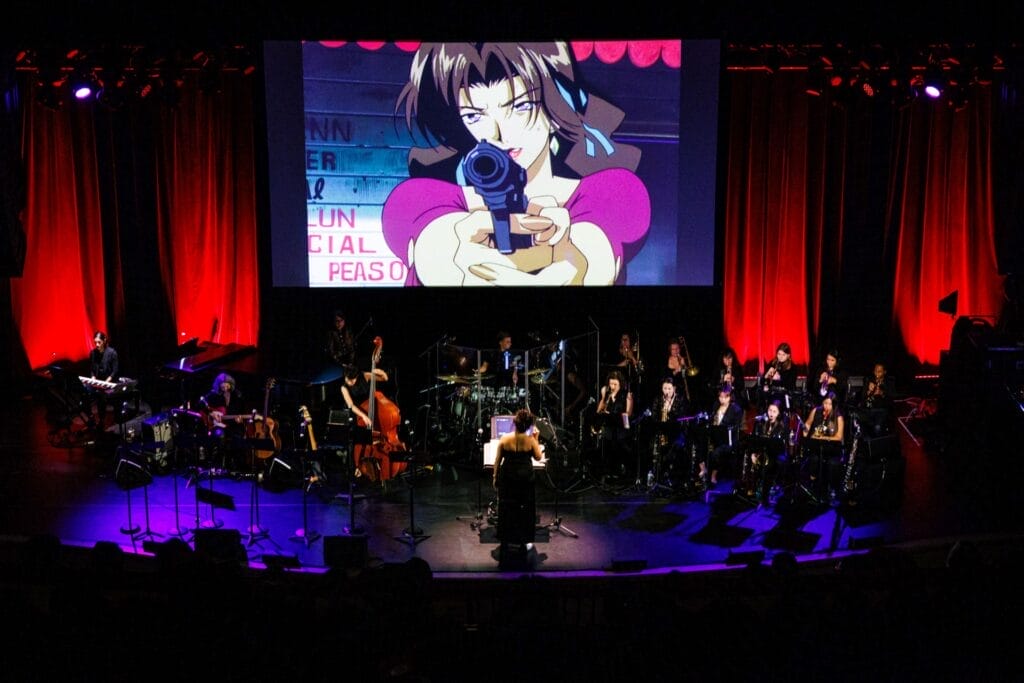 Photo of The Sinfionetta performing onstage at The Town Hall in front of a large screen, which features footage from the first episode of Cowboy Bebop.