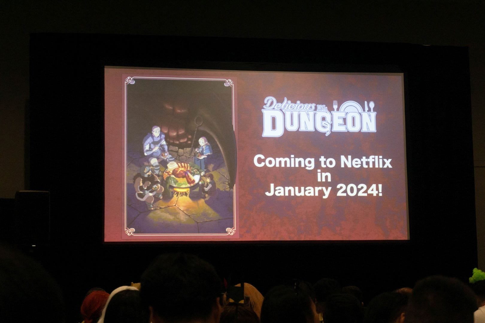 Photo from the Delicious In Dungeon premiere at Anime NYC, depicting a screen that features the show's key visual, along with the text "Delicious in Dungeon: Coming to Netflix in January 2024!"