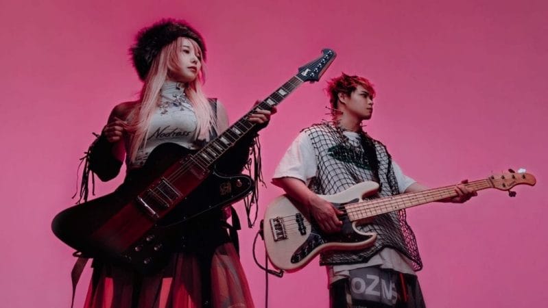J-rock group Co shu Nie poses with their instruments in front of a pink background.