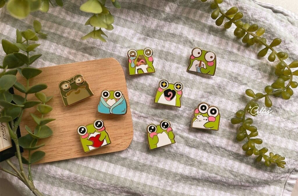 Pins made by Celtis, which feature cute, chibi-style frogs.