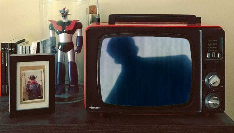 A CRT TV set up next to a figure of Gigantor. A still from Evangelion ReDeath is playing on it