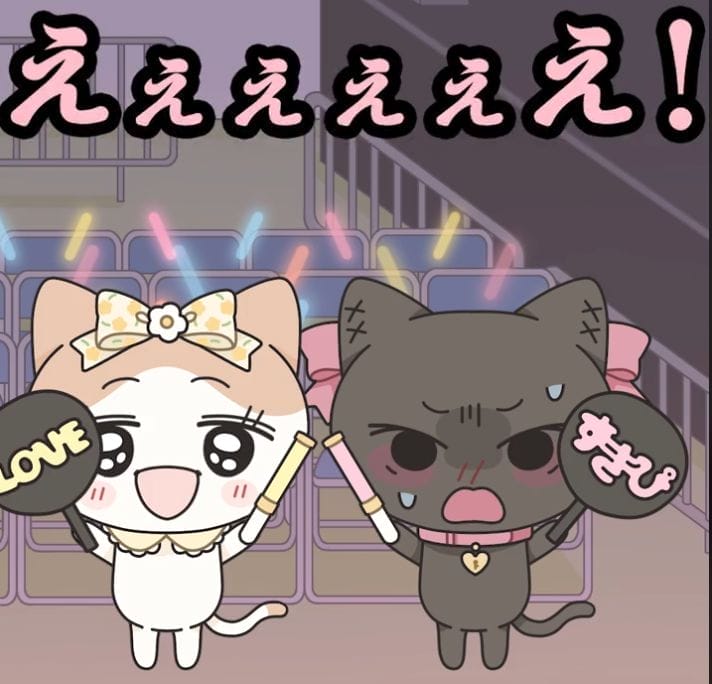 Screenshot from Otaku-chans that depicts two kittens waving paddles and glowsticks. The kitten on the left is a calico cat with a bow in her hair, holding a paddle that reads "LOVE." The right kitten is a black, blushing cat holding a sign that reads "Suki-pi." The text reads "Eeeeeeh!"