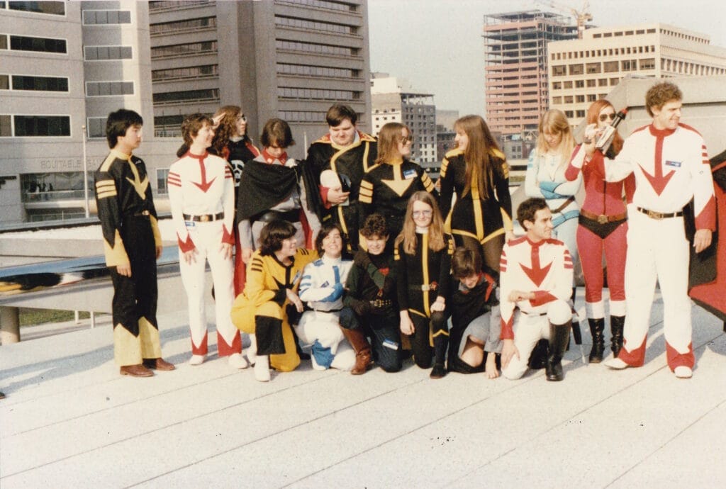Photograph taken at Worldcon 1983 that depicts sixteen Star Blazers cosplayers on top of the Baltimore Convention Center roof.