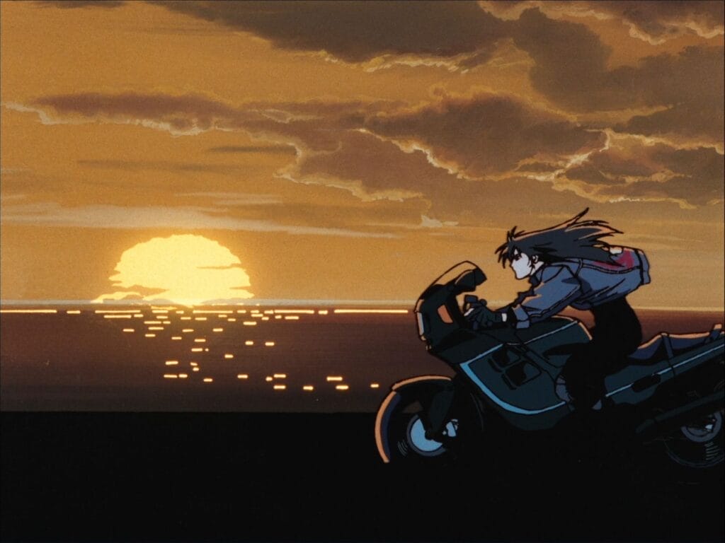 Screenshot from Angel Cop that features a woman on a motorcycle riding along the shore as the sun sets behind her