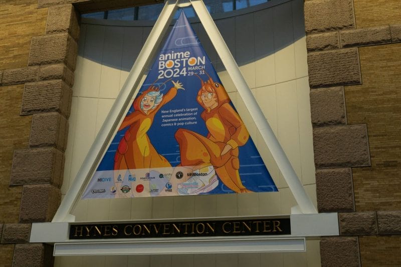 A photograph of the Anime Boston 2024 sign, which depicts the event's mascots dressed as lobsters