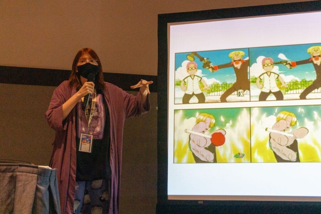 Photo of YouTuber Red Bard standing next to a projection of image comparisons between the unedited verisons of One Piece and their 4Kids-censored equivalents.