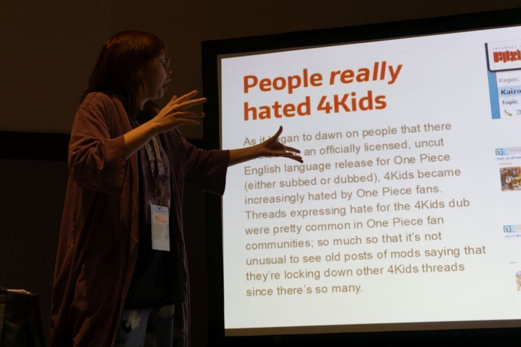 Photo of YouTuber Red Bard standing next to and gesturing at a PowerPoint slide that says "People REALLY hated 4Kids."