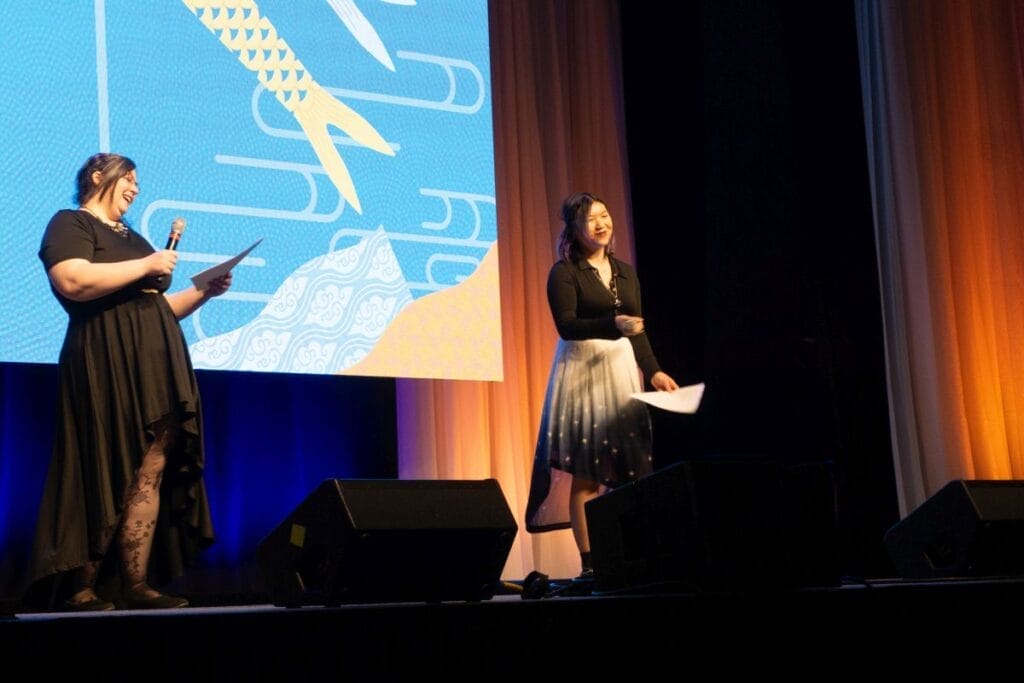 Anime Boston chairperson Jenny Leary and vice-chair Omega Au stand onstage at Anime Boston 2024's opening ceremonies