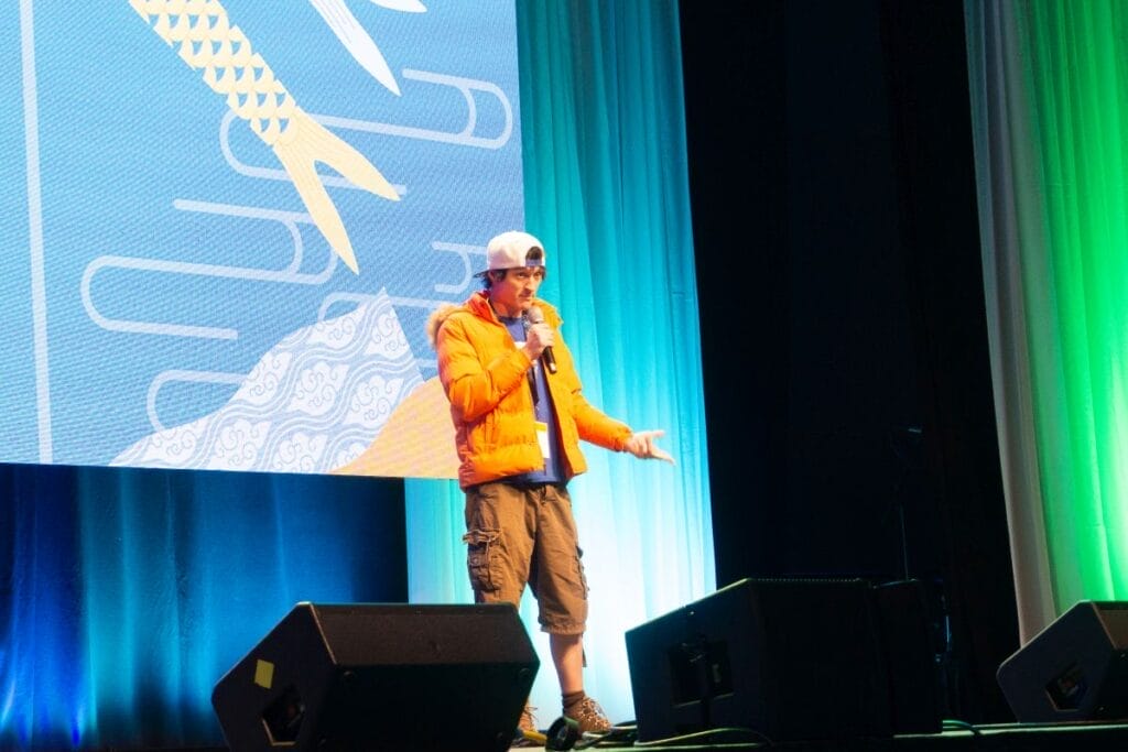 Voice actor Casey Mongillo stands onstage at Anime Boston 2024's opening ceremonies