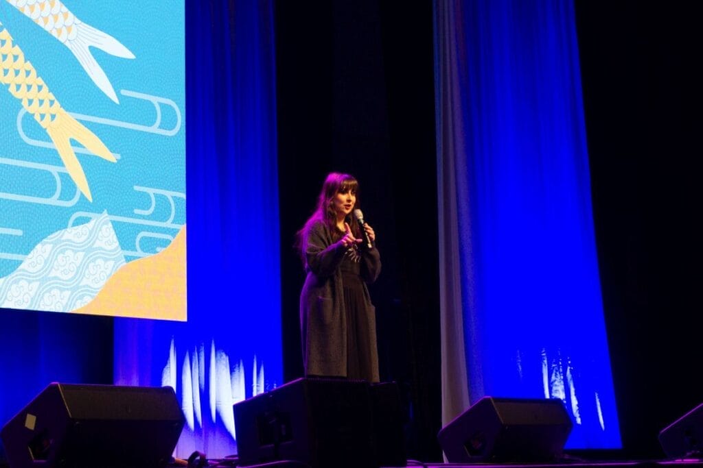 Voice actor Natalie Rial stands onstage at Anime Boston 2024's opening ceremonies