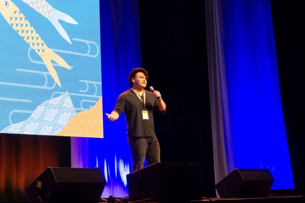 Voice actor Jack Stansbury stands onstage at Anime Boston 2024's opening ceremonies