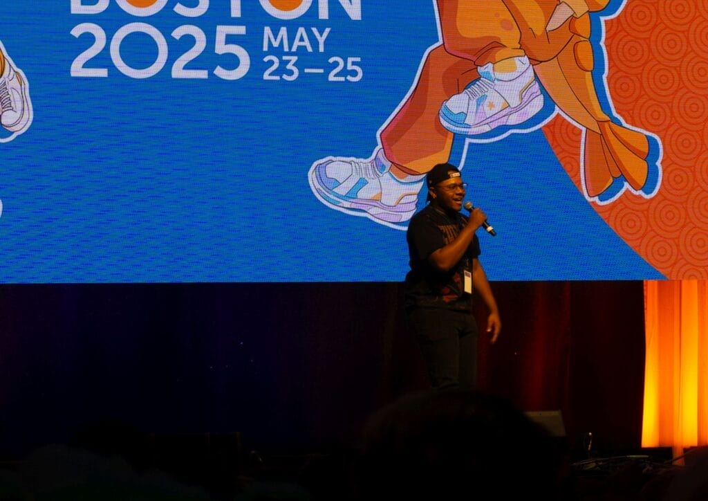 Photograph from Anime Boston 2025's opening ceremonies of AJ Beckles addressing the audience onstage