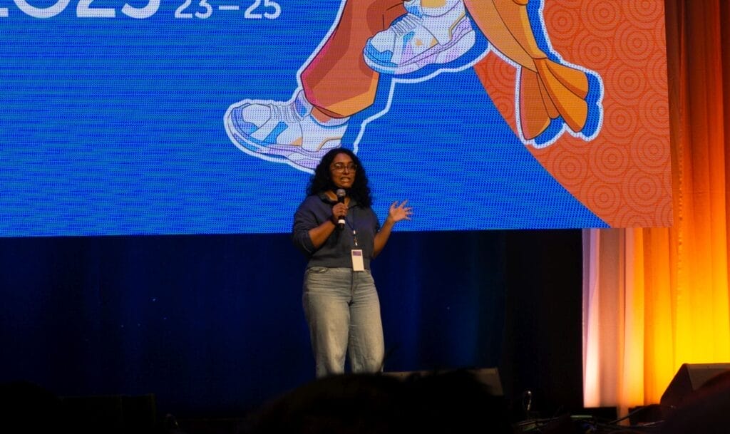 Photograph from Anime Boston 2025's opening ceremonies of Anjali Kunapaneni talking into a microphone