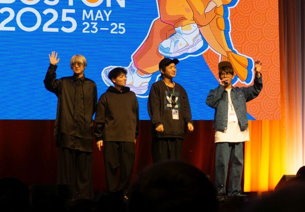 Photograph from Anime Boston 2025's opening ceremonies of the members of Blue Encount smiling as they wave at the crowd.